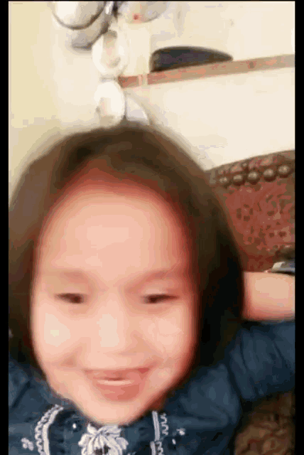 a little girl wearing a blue shirt is smiling