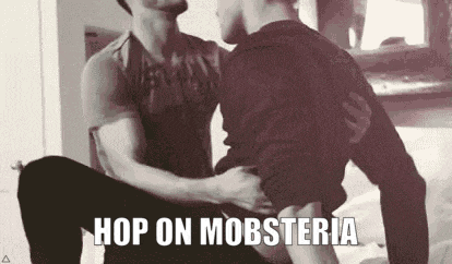 a black and white photo of two men hugging each other with the caption `` hop on mobsteria '' .