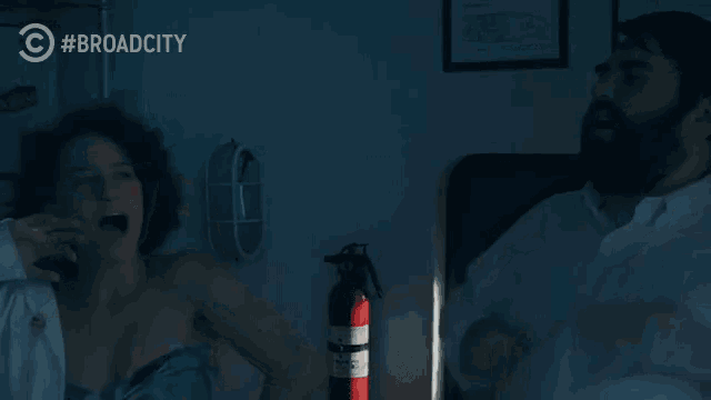 a woman laying on a bed with a fire extinguisher in front of her and the word broadcity on the bottom
