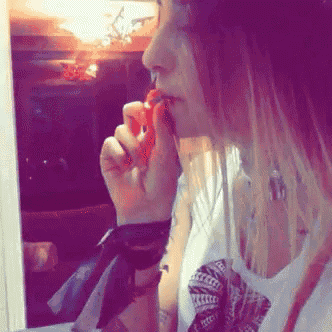 a woman with red hair is eating something in front of a mirror .
