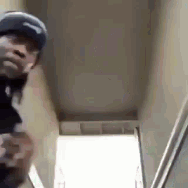 a man wearing a baseball cap is standing in a hallway .