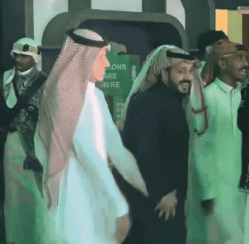 a group of men are standing in front of a green sign that says ' tions are here '
