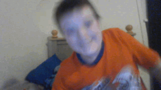 a blurry picture of a boy wearing an orange shirt with a blue collar