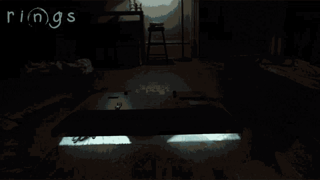 a person is crawling on the floor in a dark room with the word rings on the bottom
