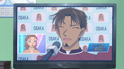 a man is talking into a microphone in front of a wall that says osaka on it