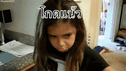 a girl with long hair is making a funny face in a room with a sign in a foreign language