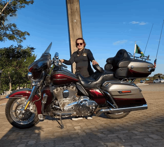 a woman is standing next to a red harley davidson motorcycle