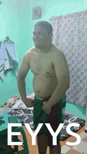 a shirtless man stands in a room with the word eyys on the bottom right