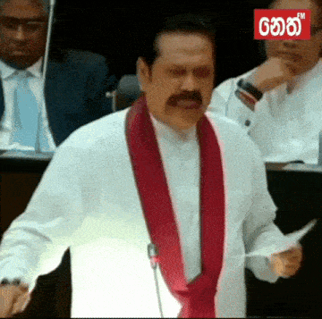 a man with a mustache is giving a speech in front of a microphone with fm in the corner