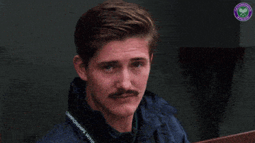 a man with a mustache is wearing a jacket that says championships with wimbledon on it