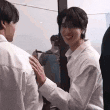 a man in a white shirt is touching another man 's back .