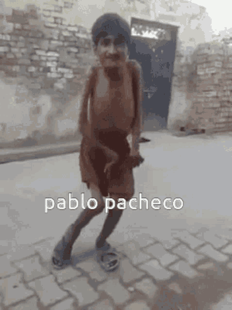 a young boy is dancing in front of a brick wall with the name pablo pacheco on the bottom