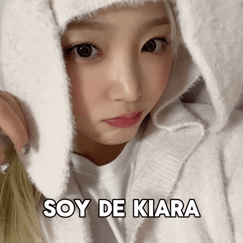 a woman wearing a white sweater with the words soy de kiara above her