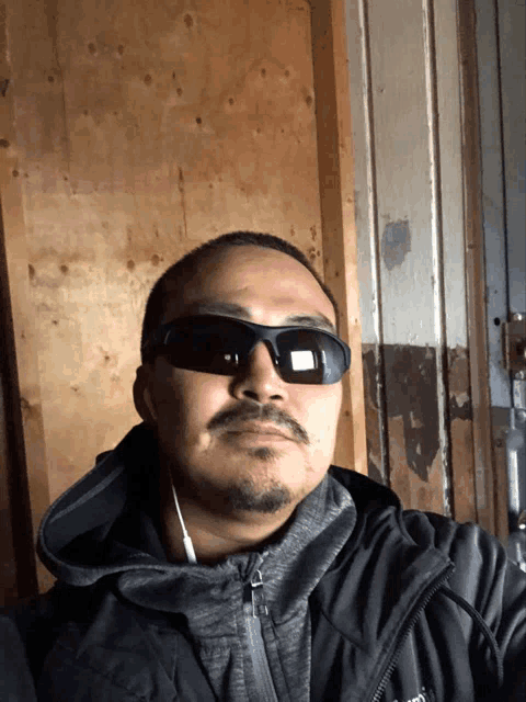 a man wearing sunglasses and a jacket with the word north face on the front
