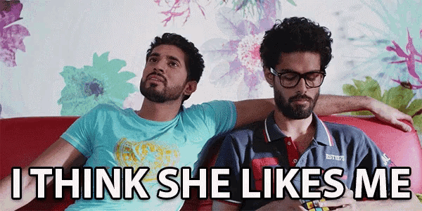 two men are sitting on a couch with the words " i think she likes me "