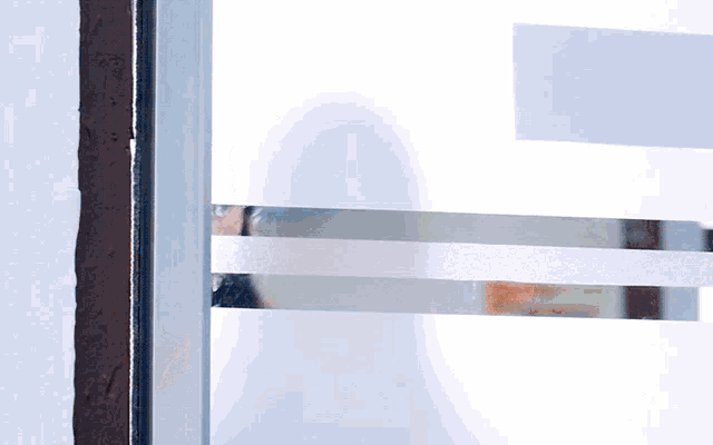 a reflection of a person in a window with a sign that says ' no smoking '