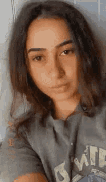 a young woman is taking a selfie while wearing a t-shirt .