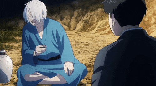 a man in a blue kimono sits on the ground next to another man