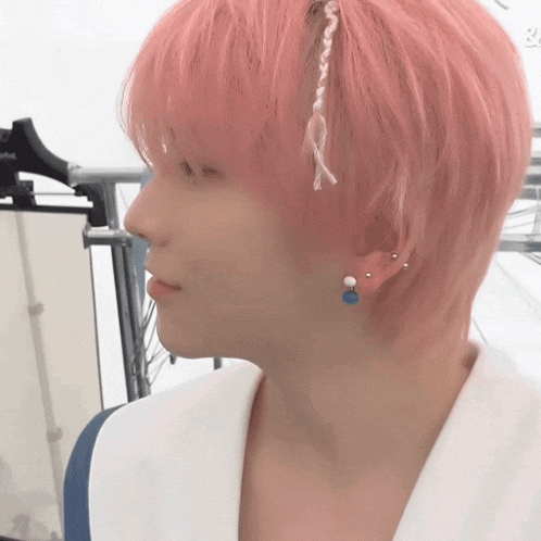 a person with pink hair and blue earrings