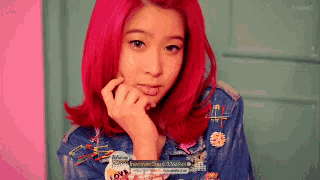 a woman with red hair is wearing a denim jacket and a shirt with the word love on it
