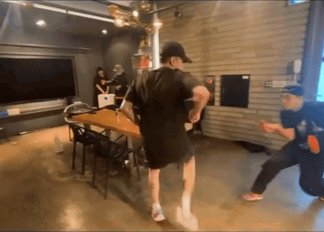 two men are dancing in a room with a table and chairs in the background .