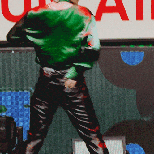 a man in a green jacket and black pants is dancing in front of a sign that says u.s. air