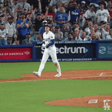 a dodgers baseball player swings his bat in front of a banner for spectrum