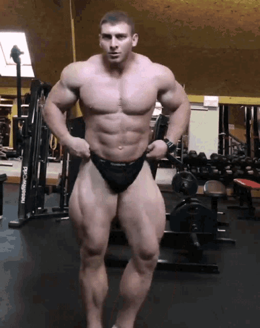 a muscular man stands in front of a machine that says ptc-d