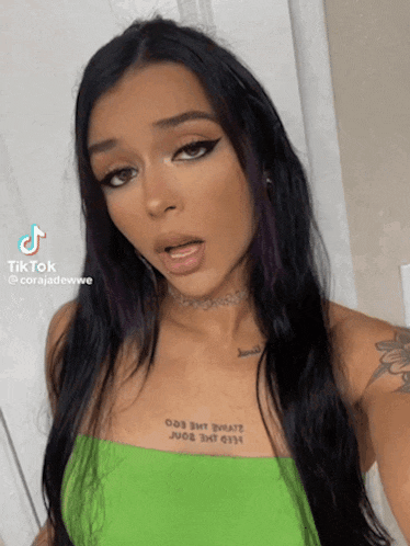 a woman with a tattoo on her chest is taking a selfie for tiktok