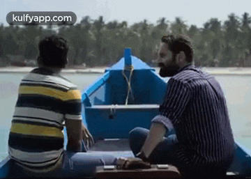 two men are sitting on a boat in the water talking to each other .