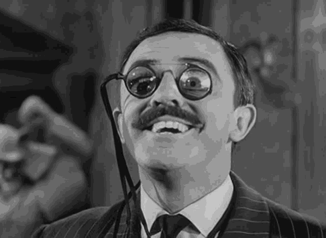 a man with a mustache and glasses is smiling