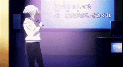 a man is singing into a microphone in front of a large screen with chinese writing on it