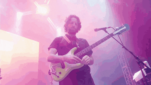 a man playing a guitar and singing into a microphone on a stage