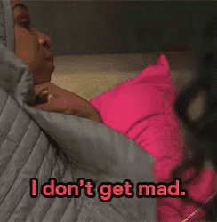 a woman in a hooded jacket is holding a pink pillow and says i don 't get mad