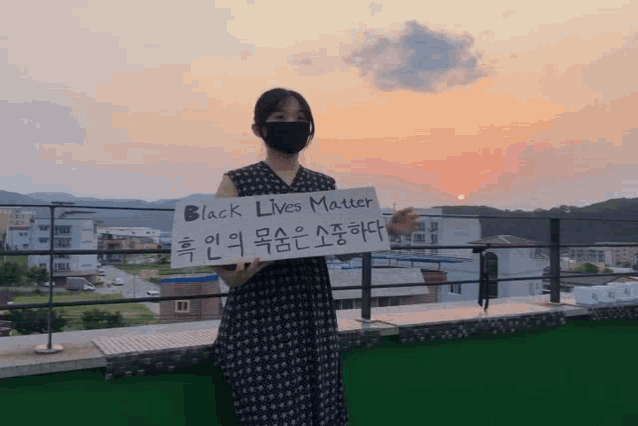 a woman wearing a black mask holds a sign that says black lives matter