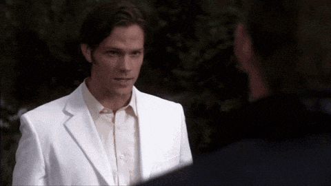 a man in a white suit is looking at another man
