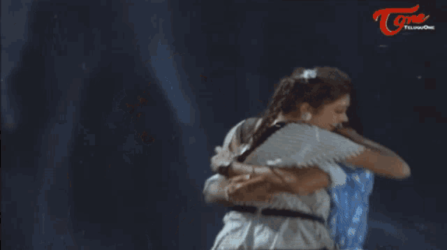 a man with a mustache is hugging a woman in front of a screen that says tone