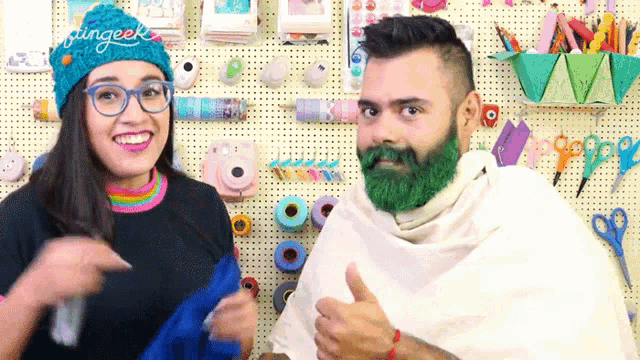 a man with a green beard is giving a thumbs up next to a woman with glasses