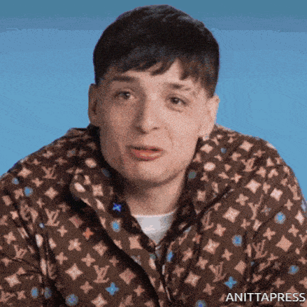 a man is wearing a louis vuitton jacket and making a funny face .