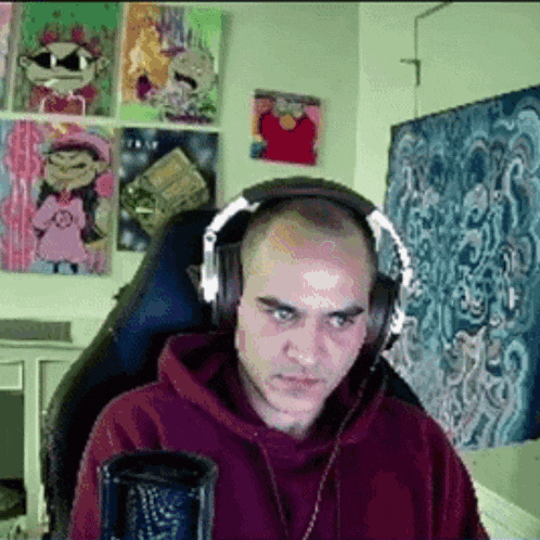 a bald man wearing headphones is sitting in front of a microphone .