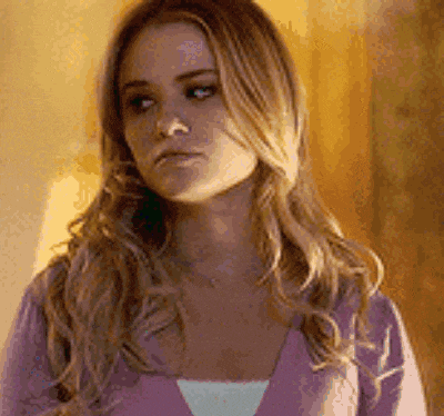 a woman with long blonde hair is wearing a purple sweater and a white tank top .