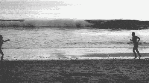 a man and a woman are running on the beach .