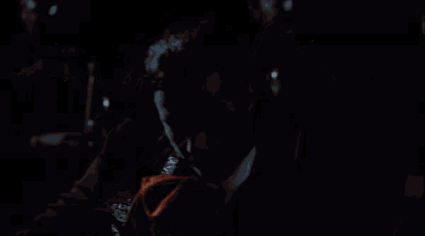 a man in a mariachi outfit is singing into a microphone in a dark room