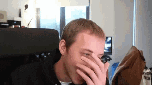a man covering his face with his hand while wearing a shirt that says ' captain red ' on it