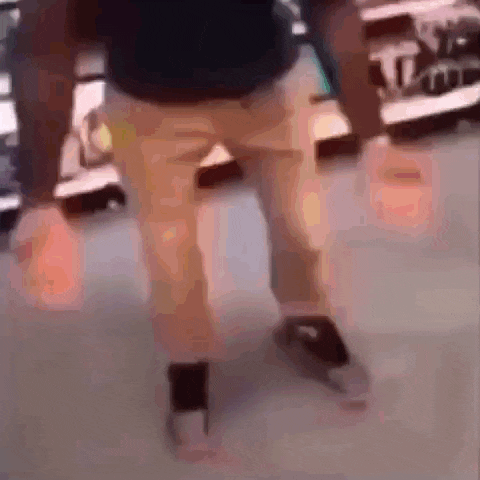 a man in a black shirt and khaki pants is dancing in a store while holding a bottle .