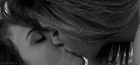 a couple of women are kissing in a black and white photo .