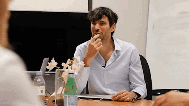 a man sitting at a table with a bottle of acqua minerale on it