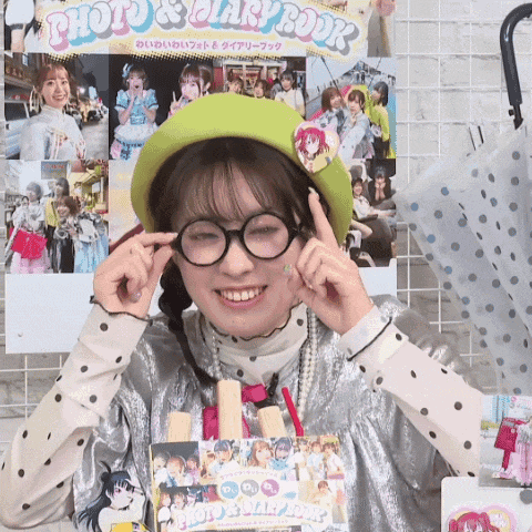 a girl wearing glasses and a green hat is smiling in front of a photo album
