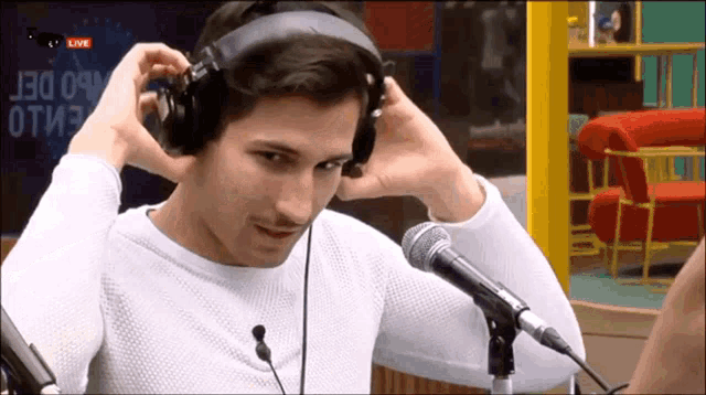 a man wearing headphones stands in front of a microphone with the word live in the background