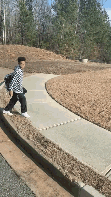 a person wearing a black and white checkered jacket is walking down a sidewalk